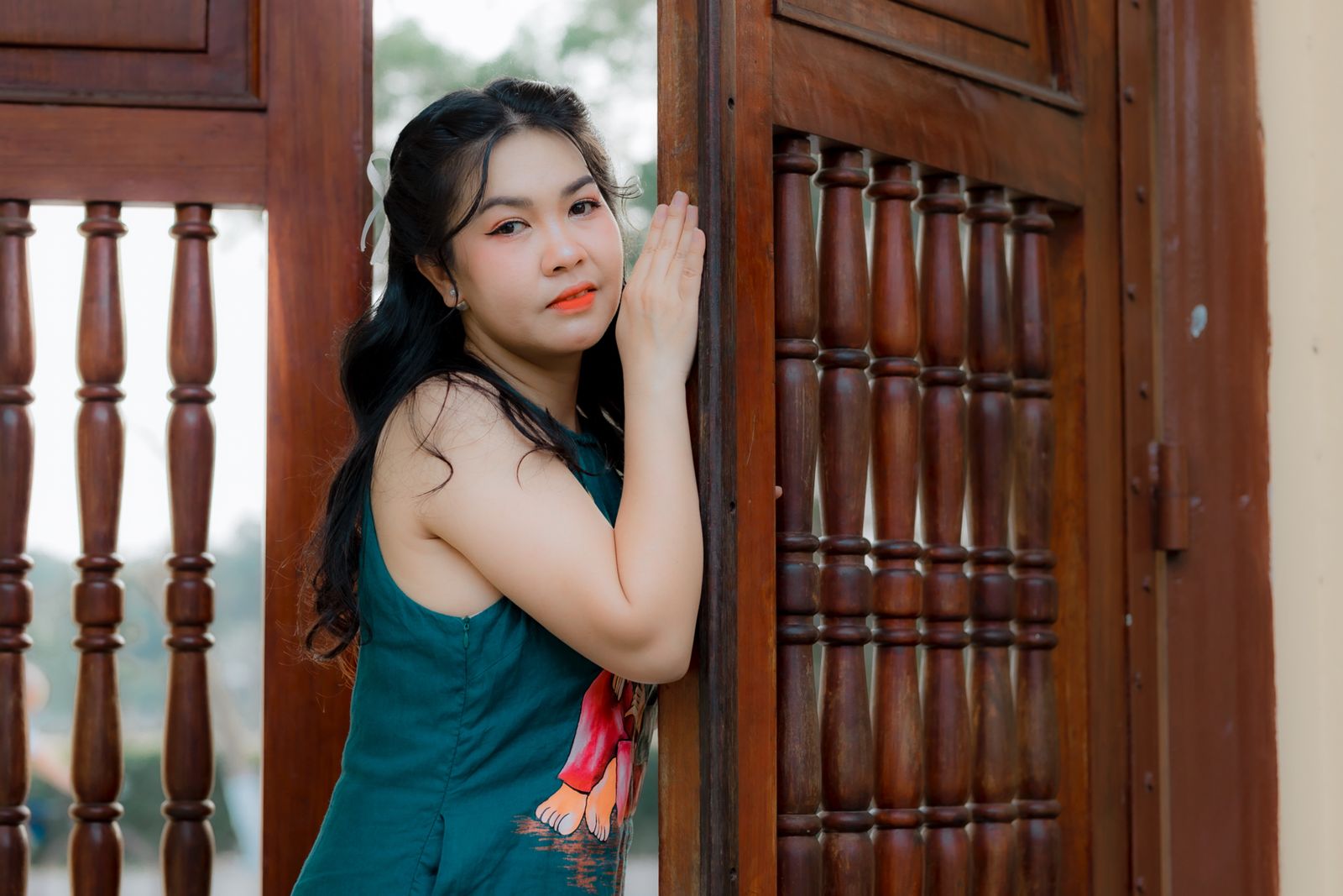 A young woman leaning quietly against a large traditional wooden door